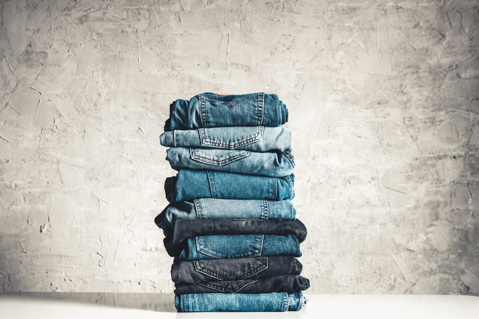 stack of blue jeans on a gray background