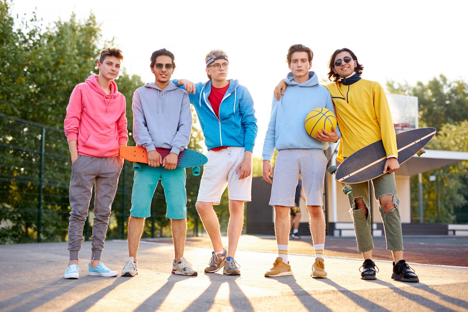 diverse young city boys are ready to play basketball together, sport club members have fun outdoors, in casual wear. portrait