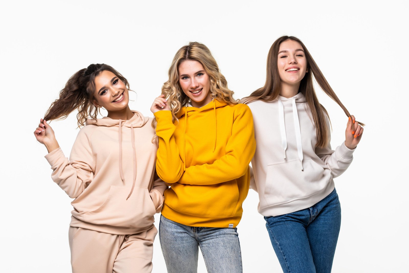 three women friends standing together and looking at the caemra on white background