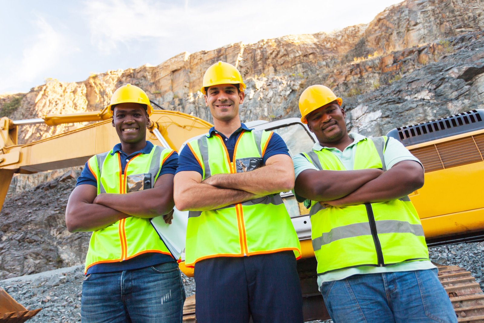 group of quarry workers standing next to excavator with arms crossed