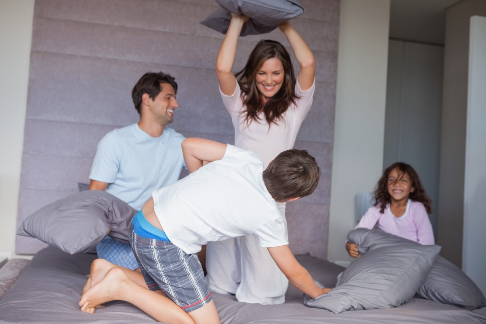 Family having a pillow fight on the bed at home
