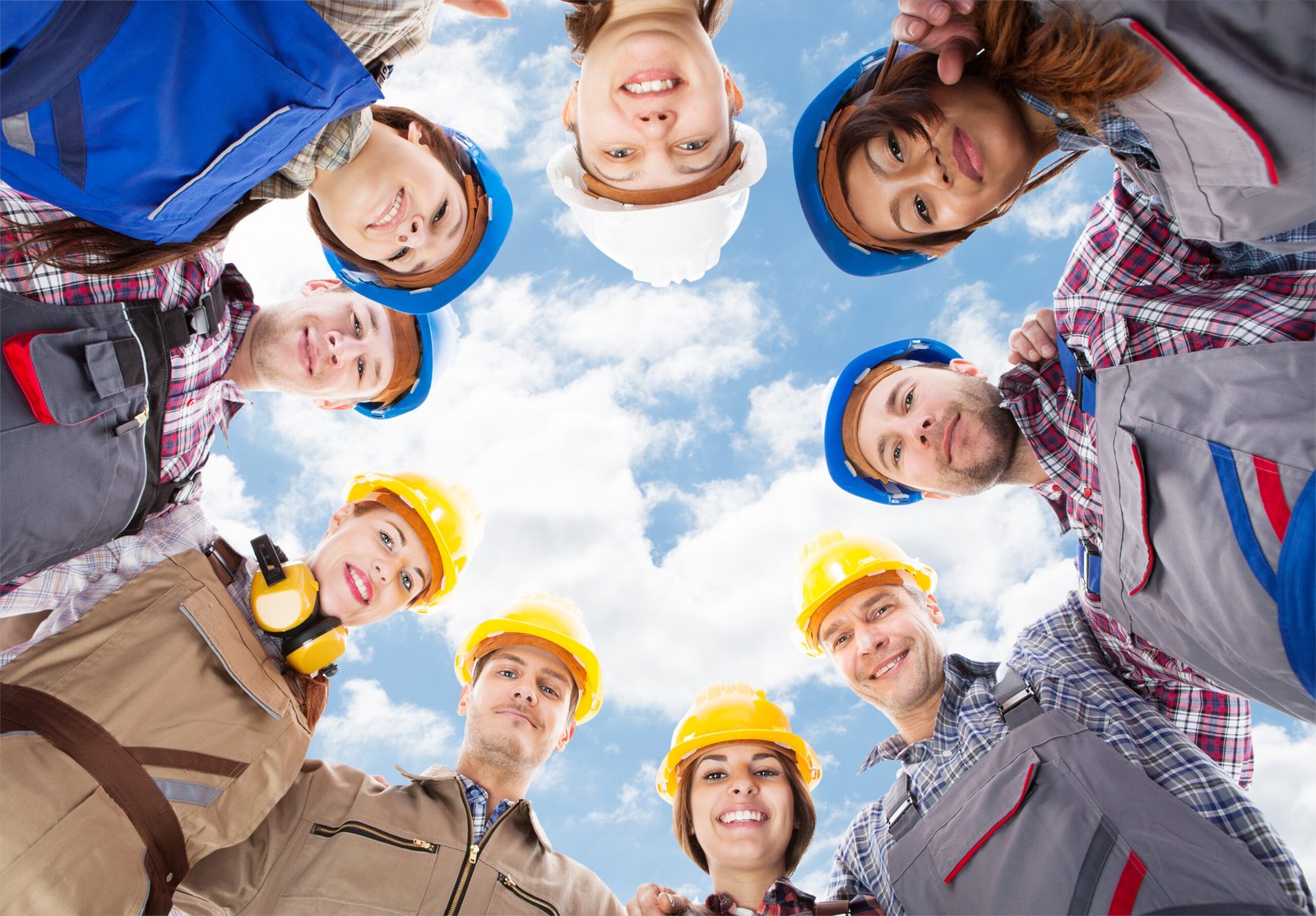Directly below portrait of multiethnic architects standing in huddle against sky